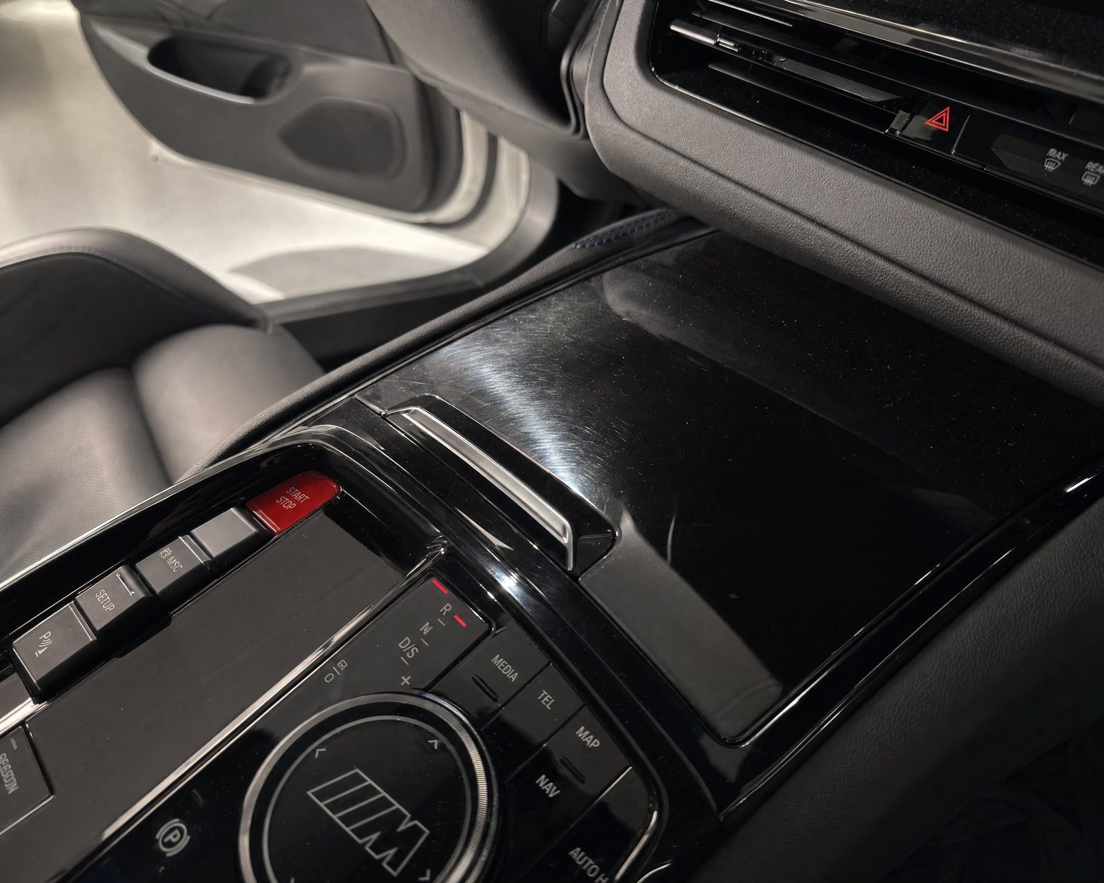 Swirls auf der Klavierlack-Blende im Cockpit eines weißen BMW M5 im Streiflicht — gezeigt im Artikel „Klavierlack im Auto reinigen“