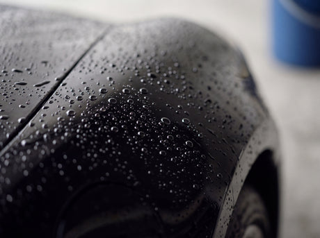 Wasserperlen auf frisch gewaschenem schwarzen Porsche Lack nach der Handwäsche mit Shampoo-Teufel